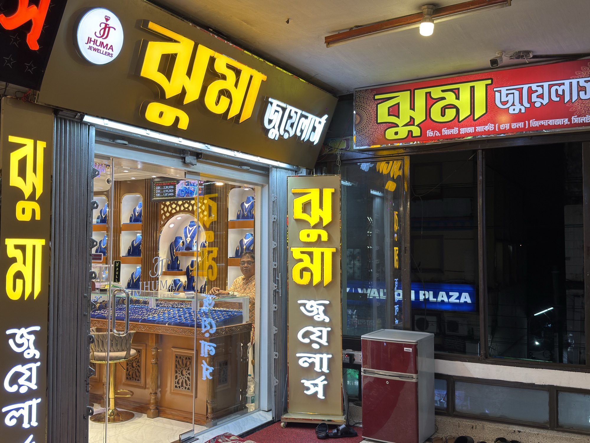 Jhuma Jewellers storefront at night with the entrance open.