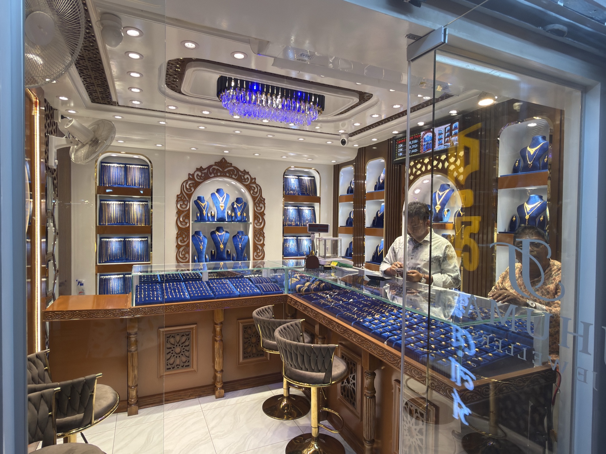 View through glass into the Jhuma Jewellers showroom at night.